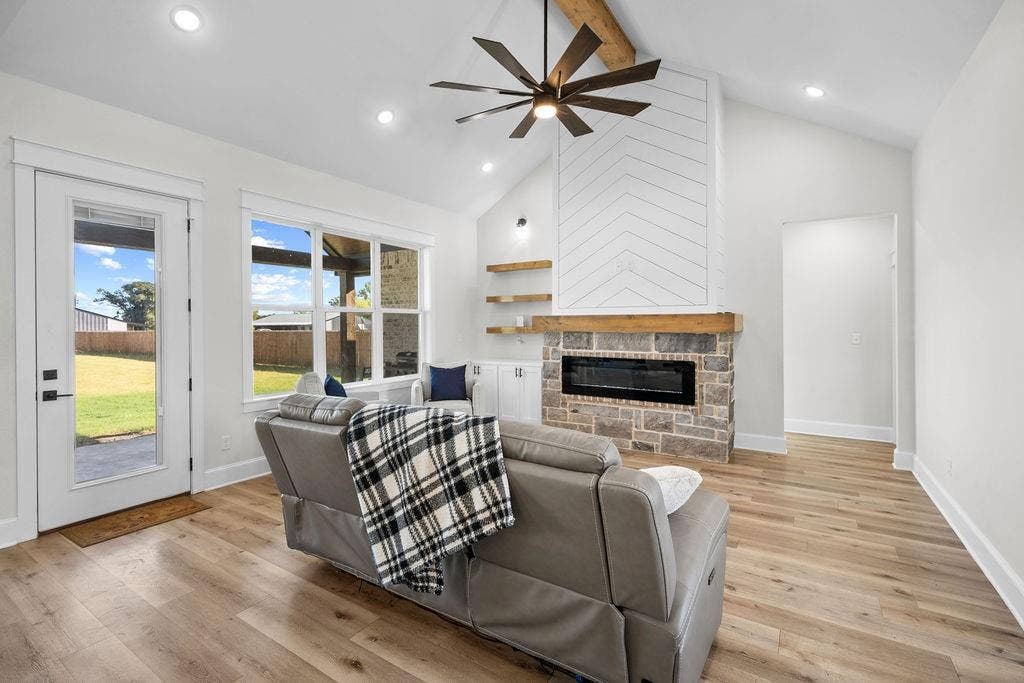 16139 Eagle Lane, Lindale, TX 75771 Vaulted ceiling with exposed wood beam, stone fireplace with a wood mantel, wood-finish flooring, recessed lighting, and large windows