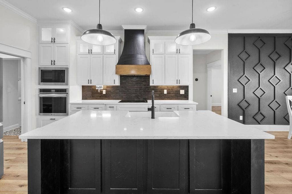 16139 Eagle Lane, Lindale, TX 75771 Kitchen island with a white countertop and integrated sink, pendant lighting, built-in stainless steel appliances, white cabinetry, and a dark tile backsplash