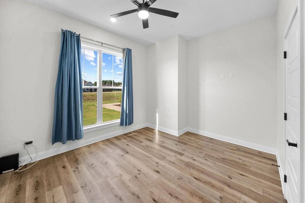 16139 Eagle Lane, Lindale, TX 75771 Wood-finish plank flooring, ceiling fan with integrated lighting, large window with white trim, and white paneled door with black hardware