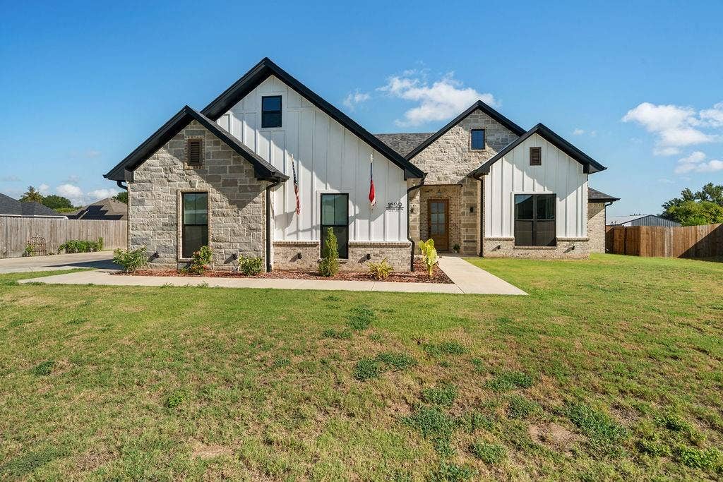 16139 Eagle Lane, Lindale, TX 75771 Stone and vertical siding exterior with dark-trimmed windows, a gabled roofline, and a concrete walkway
