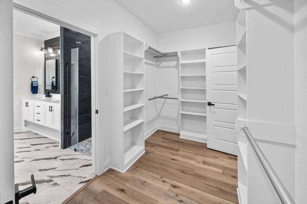 16139 Eagle Lane, Lindale, TX 75771 Custom built-in shelving, wood-finish flooring, white paneled door, and brushed nickel hanging rods