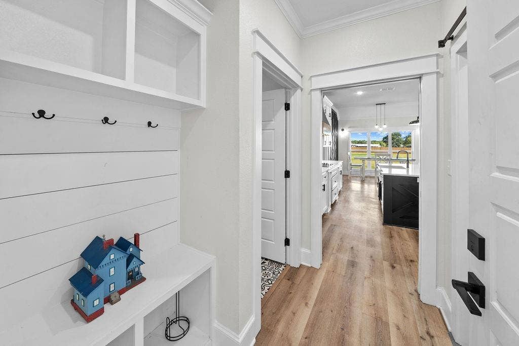 16139 Eagle Lane, Lindale, TX 75771 Built-in mudroom seating with storage, wood-finish flooring, and white paneled doors with matte black hardware