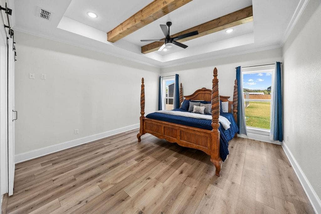 16139 Eagle Lane, Lindale, TX 75771 Tray ceiling with recessed lighting and wood beams, wood-finish flooring, two windows, and a barn door