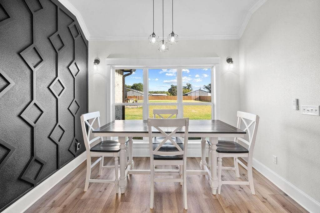 16139 Eagle Lane, Lindale, TX 75771 Accent wall with geometric trim, wood-finish flooring, large picture window, crown molding, and contemporary pendant lighting