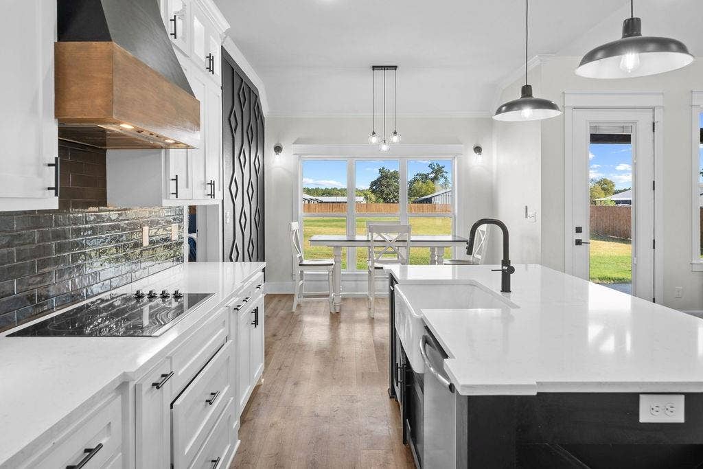 16139 Eagle Lane, Lindale, TX 75771 White shaker cabinetry, integrated cooktop, white solid surface countertops, farmhouse sink with matte black faucet, and wood-finish flooring