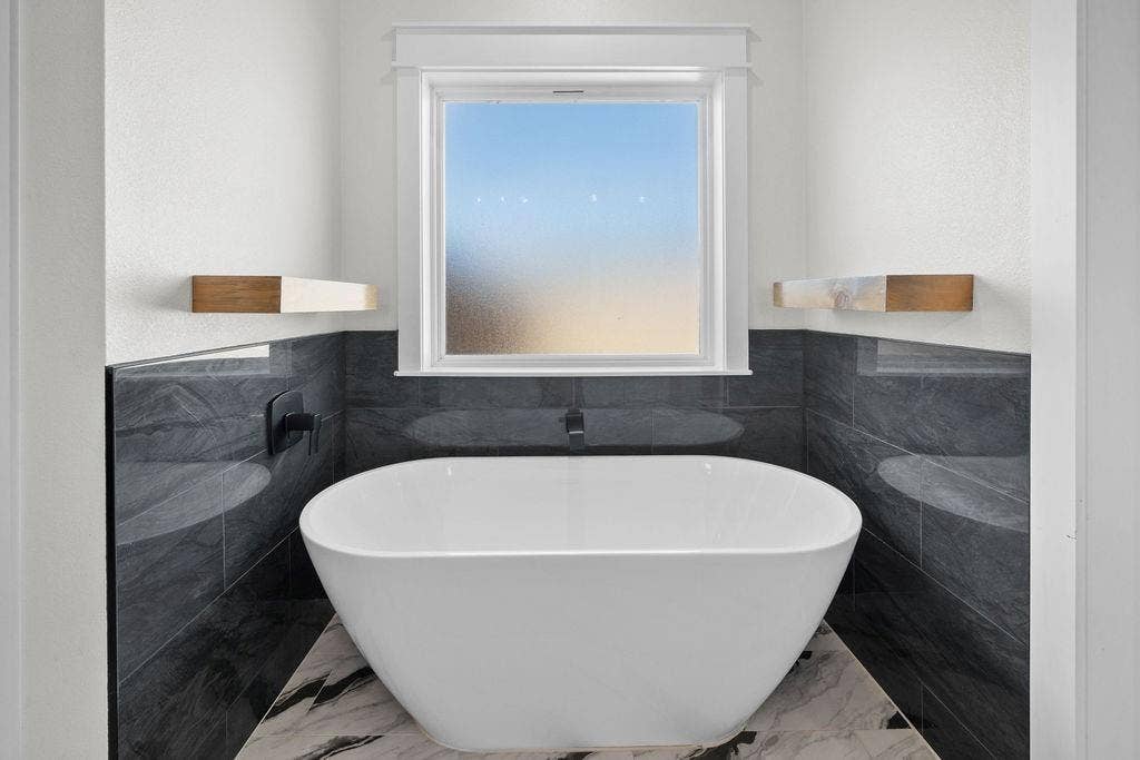 16139 Eagle Lane, Lindale, TX 75771 Freestanding soaking tub with floor-mounted faucet, dark stone tile surround, and window with white trim