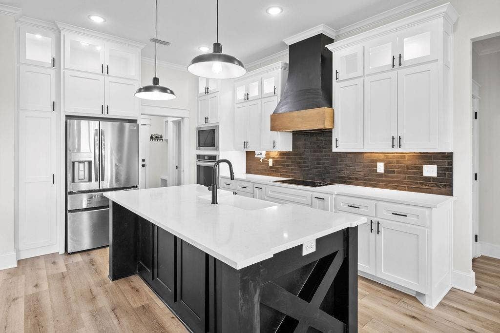 16139 Eagle Lane, Lindale, TX 75771 Gourmet kitchen featuring white shaker cabinetry, stainless steel appliances, a black wood-finish island, quartz countertops, and wood-finish flooring