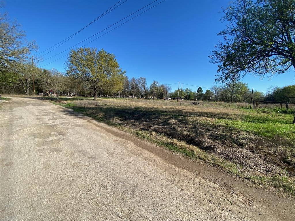 421 Kelly Lane, Seven Points, TX 75143 Expansive open land with a clear blue sky, mature trees, and existing fencing