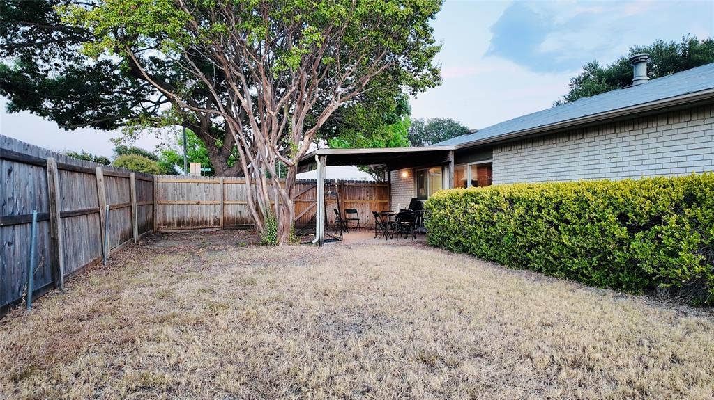 6541 Santa Fe Trail, Plano, TX 75023 Expansive backyard featuring a mature tree, privacy fencing, a covered patio, and a manicured hedge