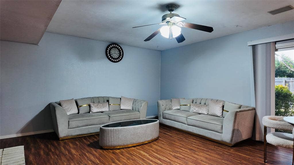 6541 Santa Fe Trail, Plano, TX 75023 Wood-finish flooring, ceiling fan with integrated lighting, light blue wall paint, and a large window with vertical blinds