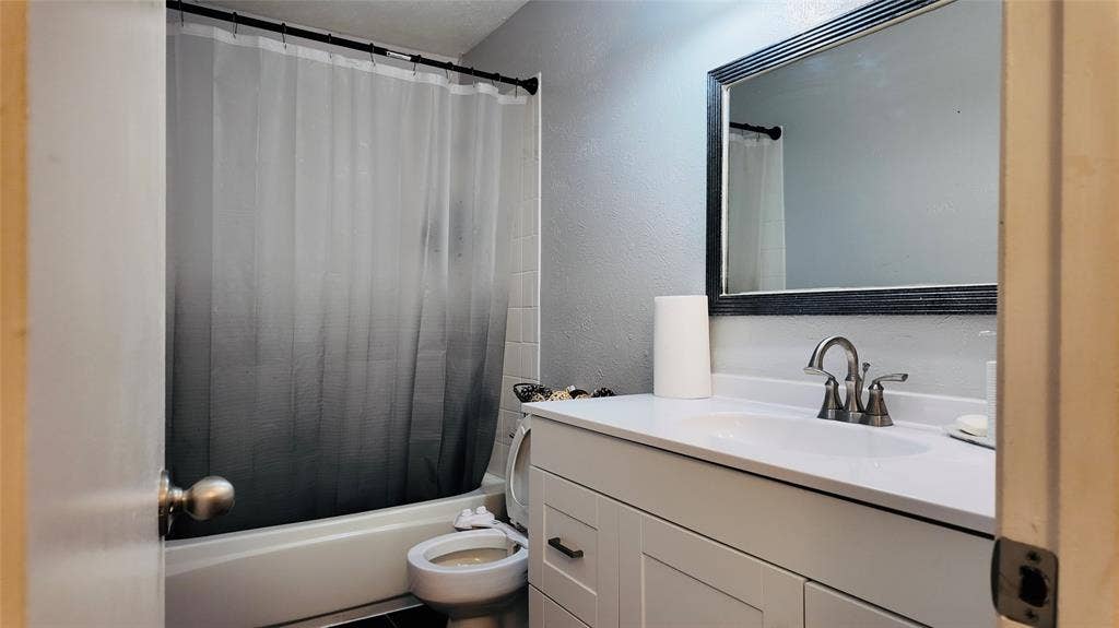 6541 Santa Fe Trail, Plano, TX 75023 White vanity with integrated sink, brushed nickel faucet, and framed mirror
