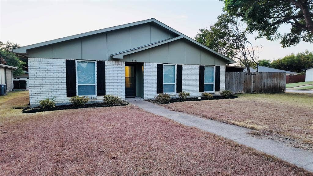 6541 Santa Fe Trail, Plano, TX 75023 Single-story residence featuring light-colored brick exterior, dark shutters, and a sloped roofline