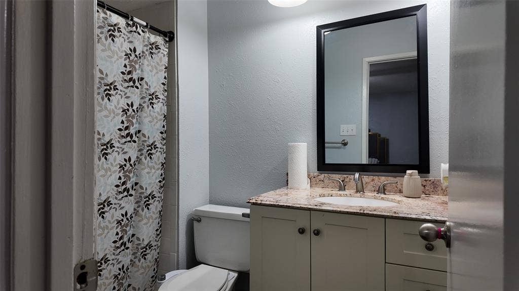 6541 Santa Fe Trail, Plano, TX 75023 Bathroom featuring a single vanity with a stone countertop, an undermount sink, and a framed mirror