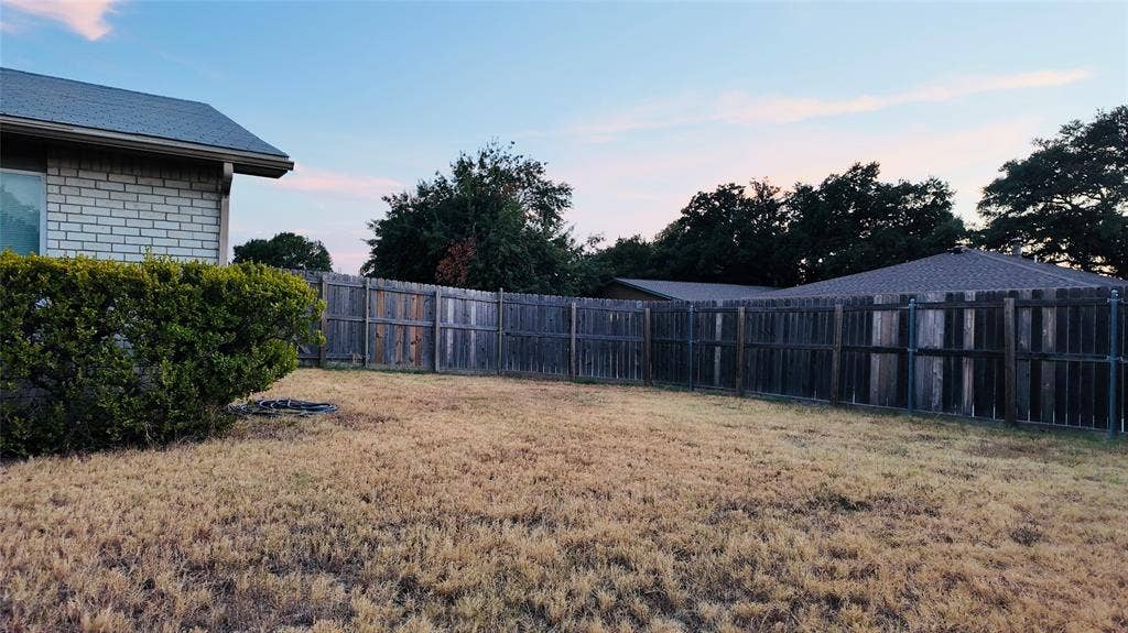 6541 Santa Fe Trail, Plano, TX 75023 Fenced backyard with mature perimeter trees, brick exterior, and a shingled roofline