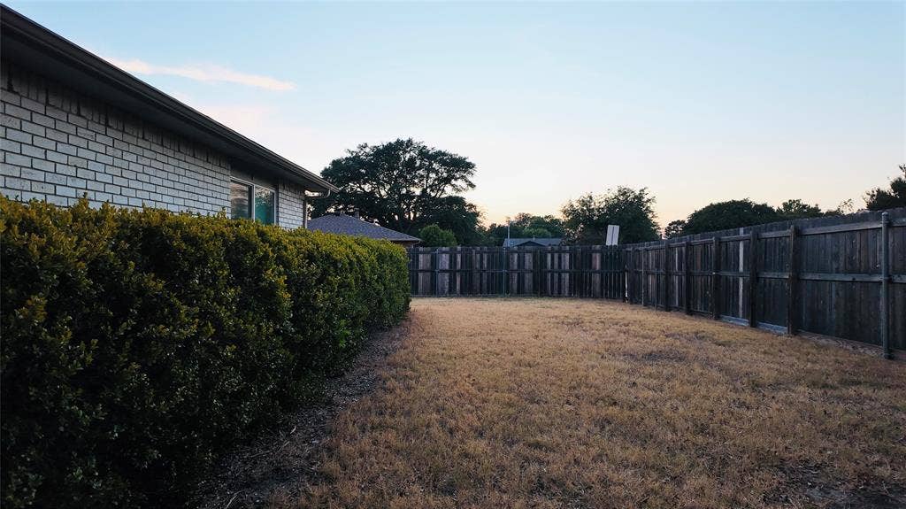 6541 Santa Fe Trail, Plano, TX 75023 Fenced backyard featuring a brick exterior, well-maintained shrubbery, and a wood fence enclosure