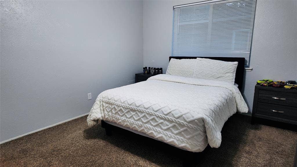6541 Santa Fe Trail, Plano, TX 75023 Neutral wall color with textured finish, window with horizontal blinds, and carpeted flooring