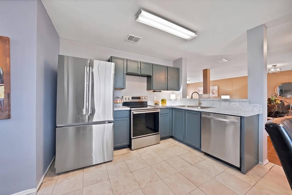 2326 Mcintosh Court, Lancaster, TX 75134 Kitchen with stainless steel appliances, light-toned tile flooring, blue cabinetry, and light-colored countertops