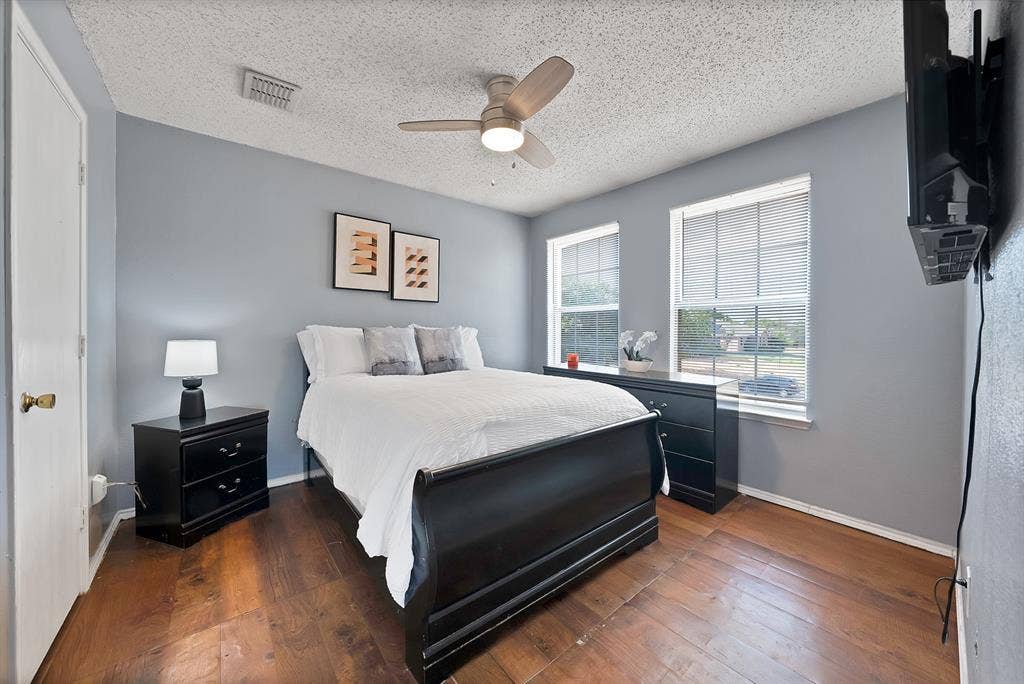 2326 Mcintosh Court, Lancaster, TX 75134 Hardwood-finish flooring, two large windows with blinds, ceiling fan with integrated lighting, textured ceiling, and light blue wall paint