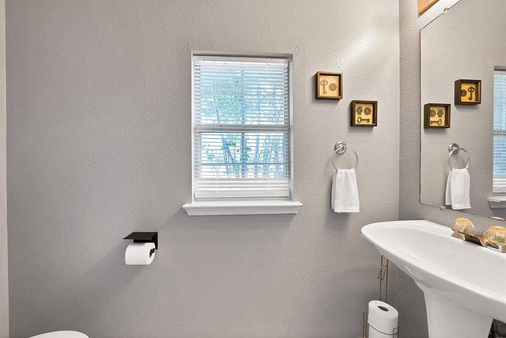 2326 Mcintosh Court, Lancaster, TX 75134 Pedestal sink with chrome fixtures, window with blinds, and a wall-mounted mirror