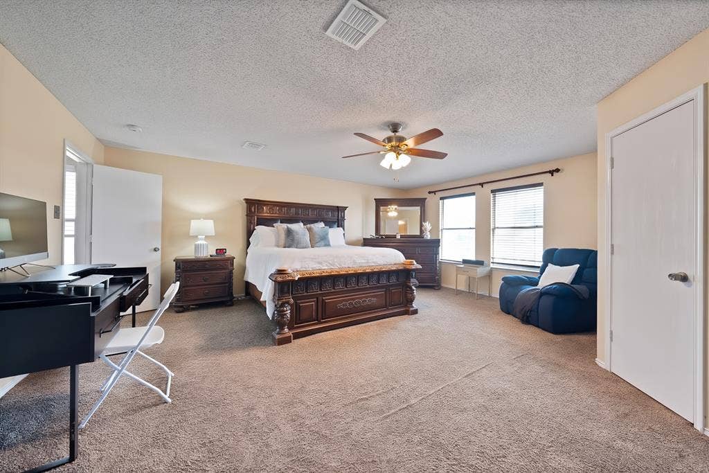 2326 Mcintosh Court, Lancaster, TX 75134 Carpeted bedroom with a ceiling fan, two windows with blinds, and neutral wall paint