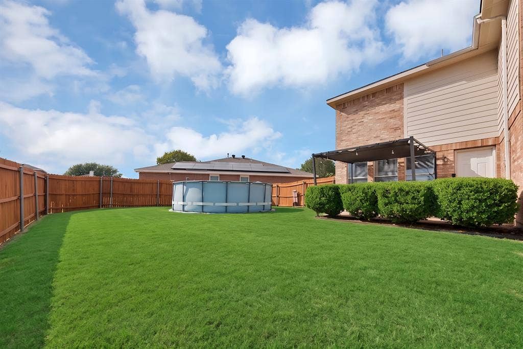 2326 Mcintosh Court, Lancaster, TX 75134 Expansive backyard with a manicured lawn, wood privacy fencing, and a brick and siding exterior
