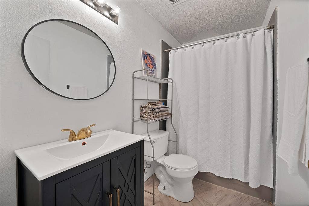 2326 Mcintosh Court, Lancaster, TX 75134 Vanity with a white integrated sink, gold-tone faucet, and dark wood-finish cabinetry