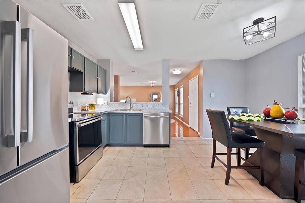 2326 Mcintosh Court, Lancaster, TX 75134 Kitchen featuring stainless steel appliances, two-tone cabinetry, tiled flooring, and a dining area with a contemporary light fixture