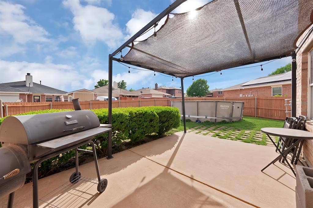 2326 Mcintosh Court, Lancaster, TX 75134 Spacious concrete patio with a shade structure, manicured hedges, and a fenced perimeter