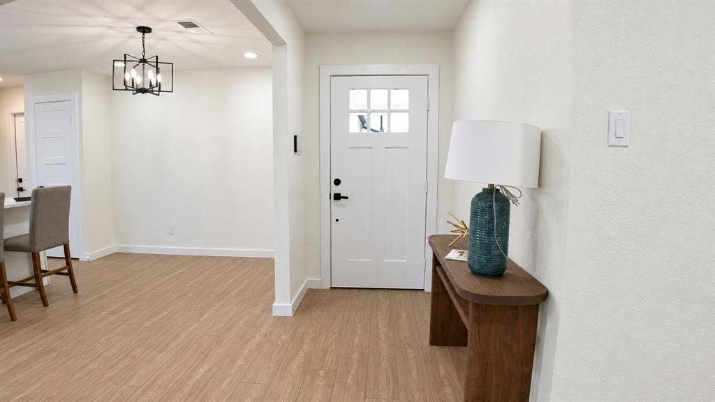 2417 Via Barcelona, Carrollton, TX 75006 Entryway featuring a white paneled door with glass inserts, wood-finish flooring, and a contemporary black chandelier