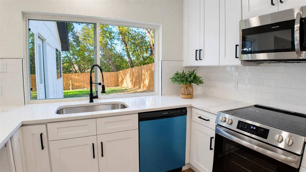 2417 Via Barcelona, Carrollton, TX 75006 White shaker cabinetry with matte black hardware, stainless steel appliances, white subway tile backsplash, white countertops, and a stainless steel sink with a black faucet