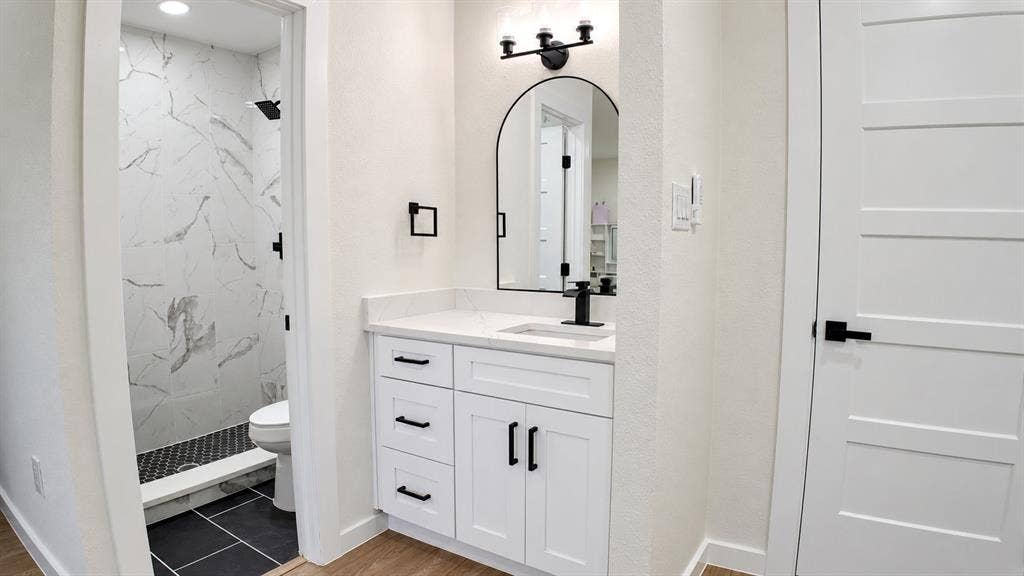 2417 Via Barcelona, Carrollton, TX 75006 White vanity with black hardware, arched mirror, black faucet, and white countertop
