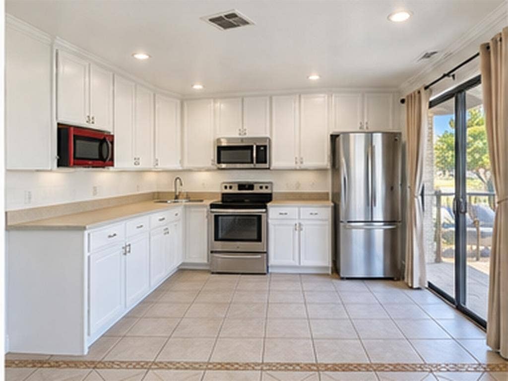 1919 American Drive, #B112, Lago Vista, TX 78645 White cabinetry with crown molding, stainless steel appliances, recessed lighting, and a sliding glass door leading to an outdoor deck