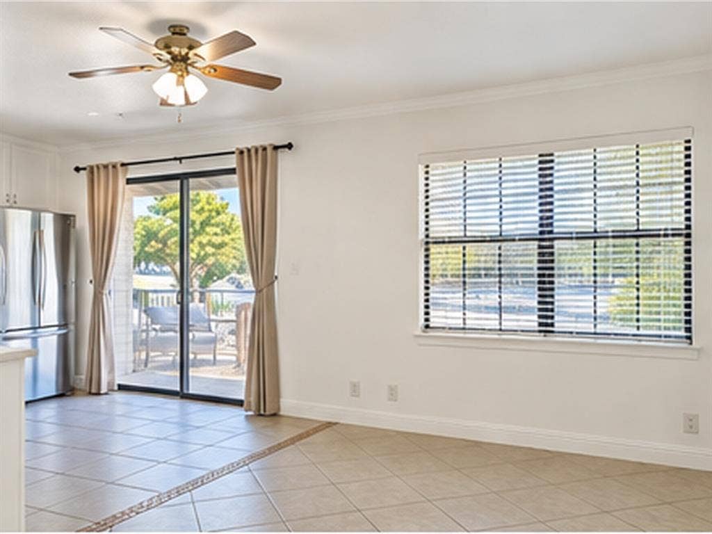 1919 American Drive, #B112, Lago Vista, TX 78645 Tile flooring with decorative inlay, sliding glass door with outdoor patio, ceiling fan with integrated lighting, and a large window with blinds