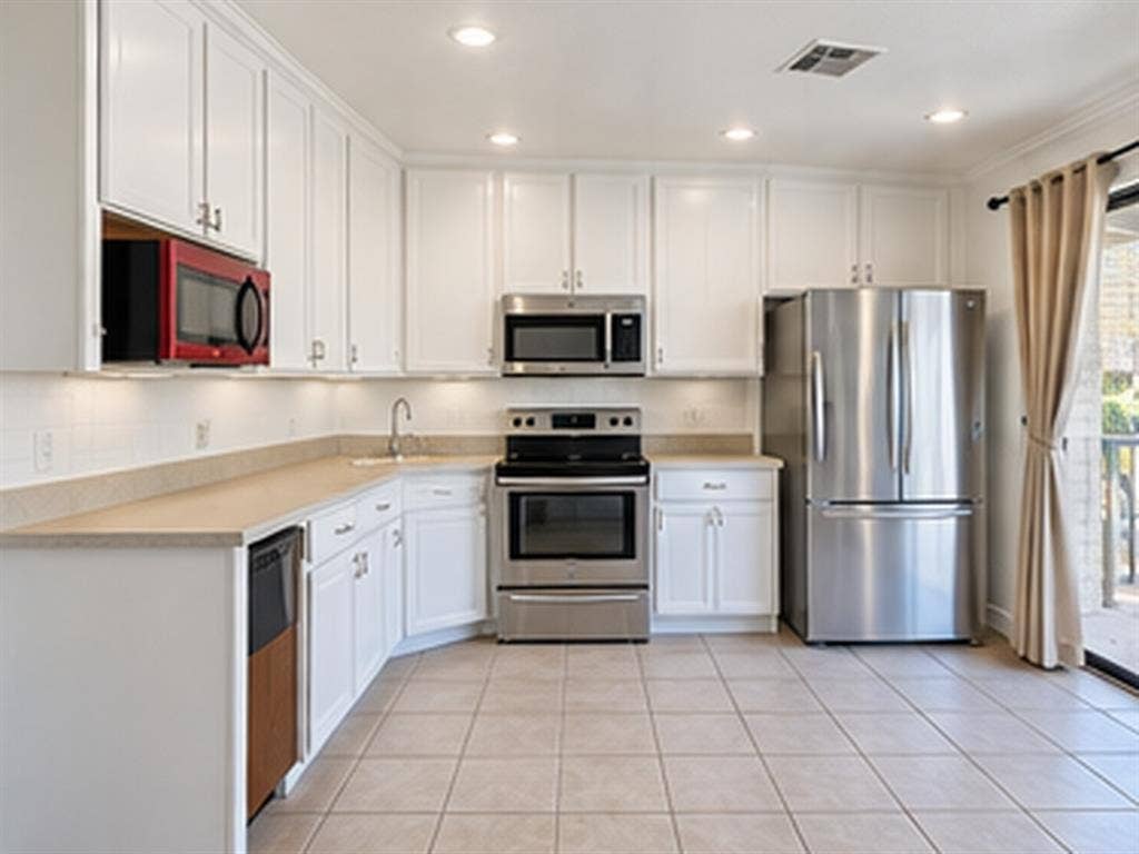 1919 American Drive, #B112, Lago Vista, TX 78645 White cabinetry, stainless steel appliances, recessed ceiling lights, tile flooring, and a sliding glass door