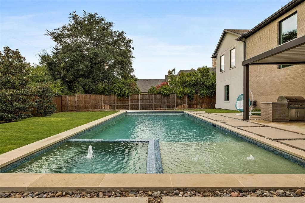5724 Charlestown Drive, Dallas, TX 75230 Expansive backyard featuring a rectangular swimming pool with integrated water features, stone coping, and a surrounding patio
