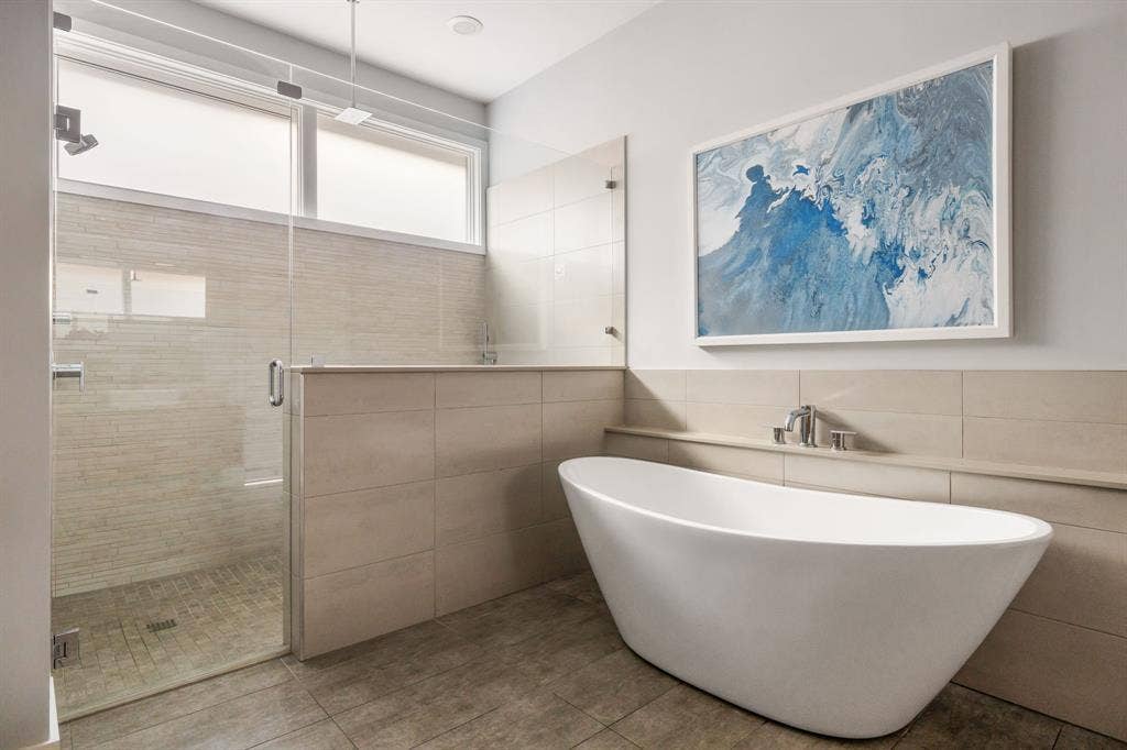 5724 Charlestown Drive, Dallas, TX 75230 Freestanding soaking tub, glass-enclosed shower, tiled half-wall, and transom windows