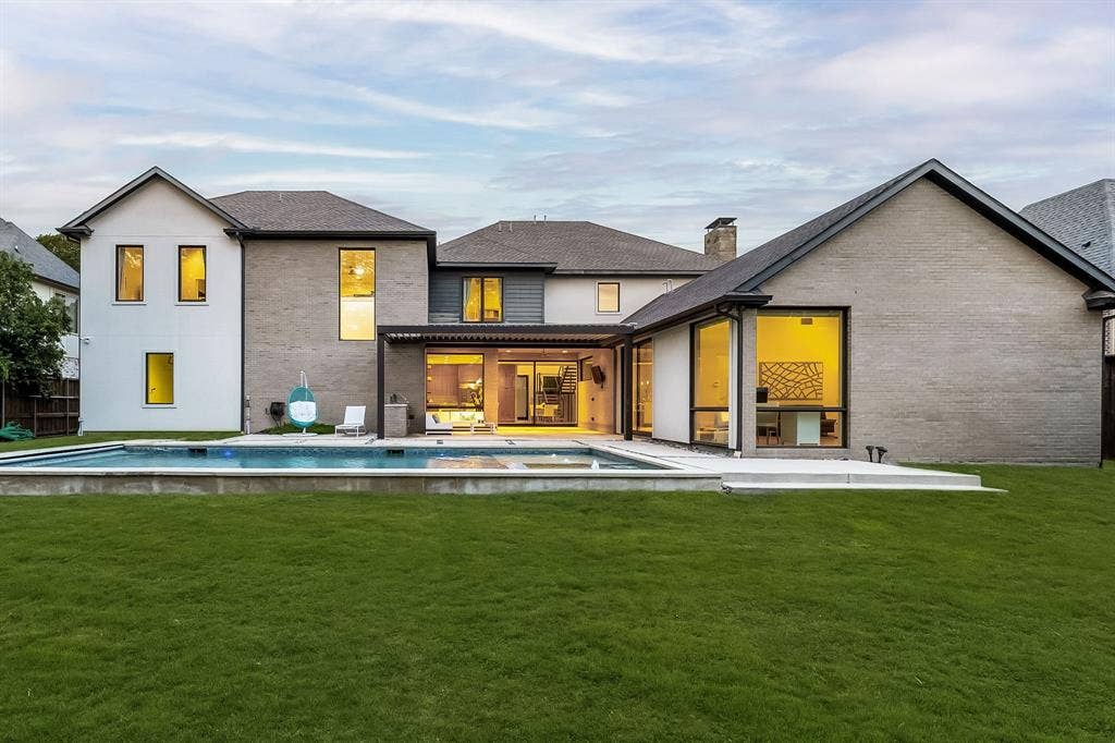5724 Charlestown Drive, Dallas, TX 75230 Expansive backyard featuring a manicured lawn, a swimming pool, and a multi-level architectural design with large windows and a covered patio area