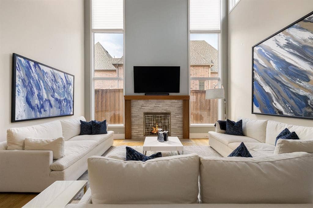 5724 Charlestown Drive, Dallas, TX 75230 Vaulted ceilings, stone-clad fireplace with wood mantel, tall windows, wood-finish flooring, and light wall tones