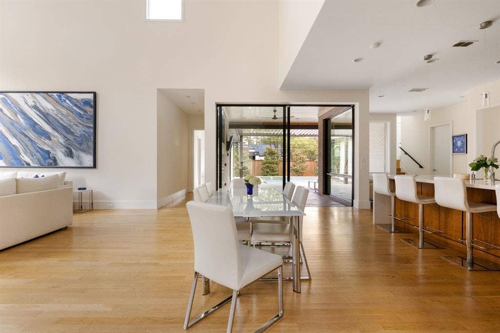 5724 Charlestown Drive, Dallas, TX 75230 Light wood-finish flooring throughout, high ceilings, large sliding glass doors, recessed lighting, and a kitchen island with bar seating