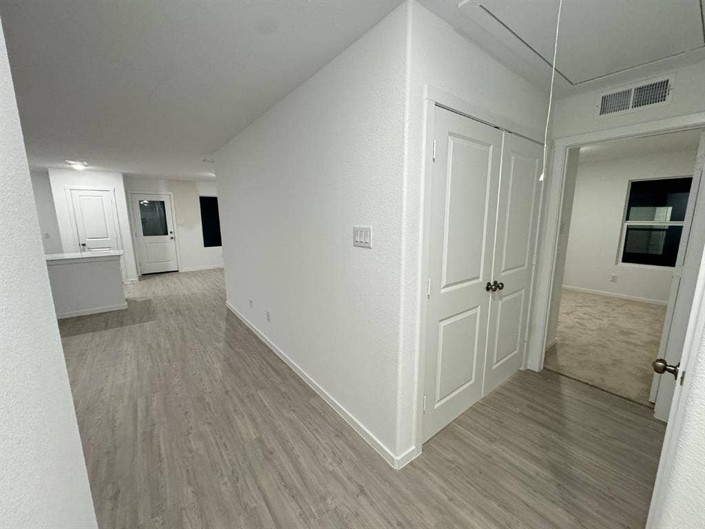 7908 Gilbert Street, McKinney, TX 75071 Wood-finish flooring extending into the living area, white paneled doors, and a built-in kitchen peninsula