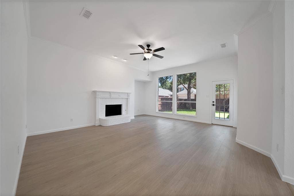 1687 Garrison Drive, Frisco, TX 75033 Large living room boasts a gas starter fireplace and large windows overlooking the good size backyard.