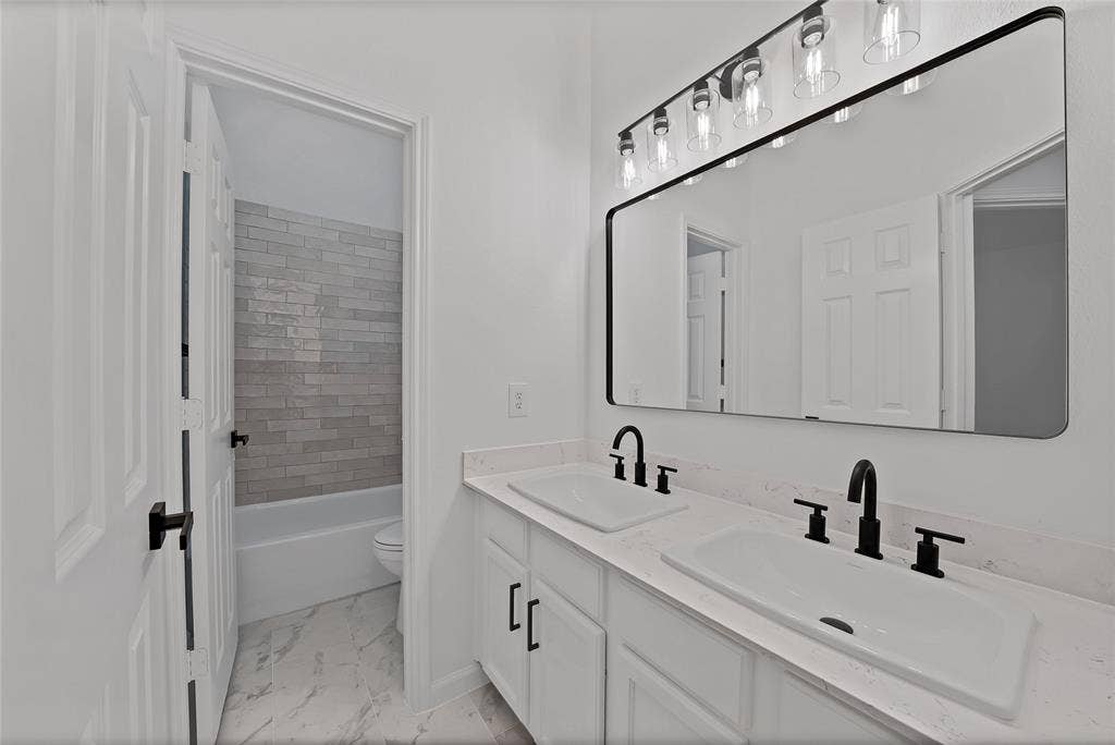 1687 Garrison Drive, Frisco, TX 75033 Gorgeous guest bathroom boasts painted cabinetry, hardware, dual sinks, designer mirror, new plumbing fixtures, lighting and tile.