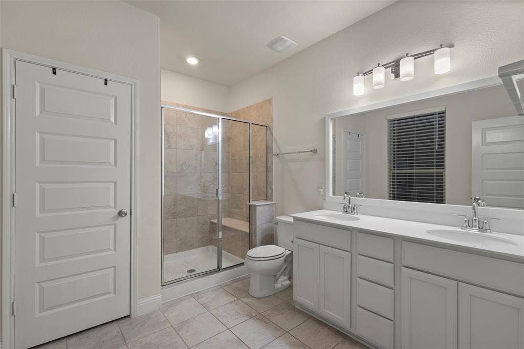 8028 Hickory Branch Drive, Frisco, TX 75034 Dual vanity with white cabinetry, a large frameless mirror, and overhead lighting