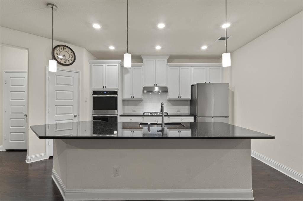 8028 Hickory Branch Drive, Frisco, TX 75034 Kitchen featuring a center island with dark countertop, white shaker cabinetry, stainless steel appliances, and dark wood-finish flooring
