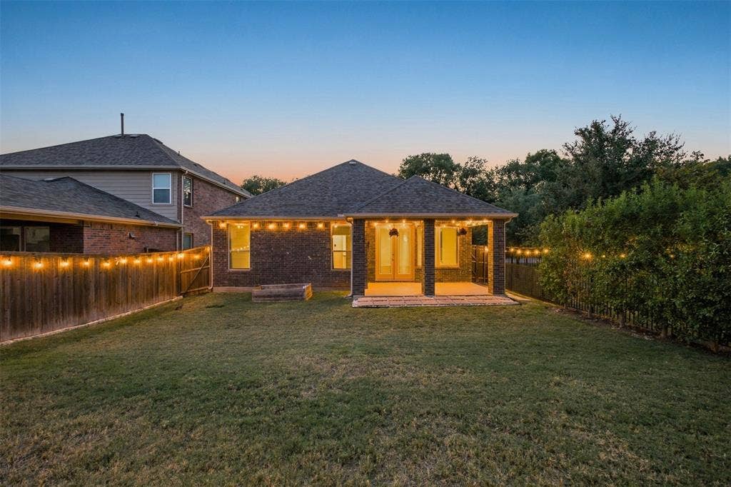 8028 Hickory Branch Drive, Frisco, TX 75034 Expansive backyard featuring a manicured lawn, wood fencing, and a covered patio with brick columns