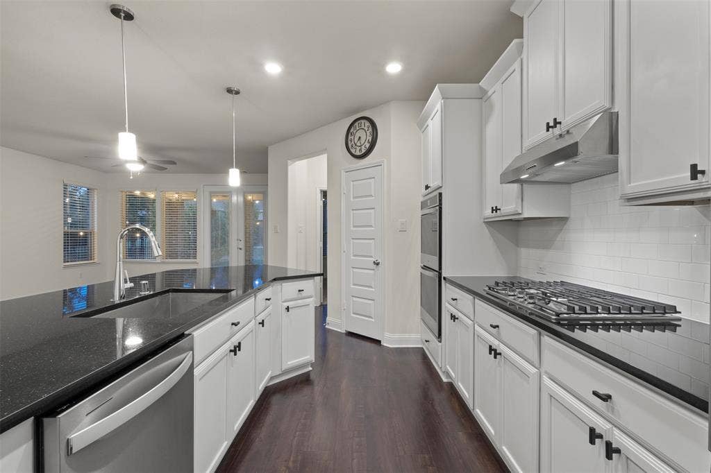 8028 Hickory Branch Drive, Frisco, TX 75034 White cabinetry with dark hardware, dark stone countertops, stainless steel appliances, and wood-finish flooring