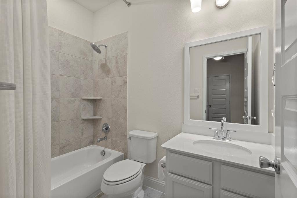 8028 Hickory Branch Drive, Frisco, TX 75034 Full bathroom featuring a white vanity with an integrated sink, a framed mirror, and a tub with tiled surround and built-in shelving