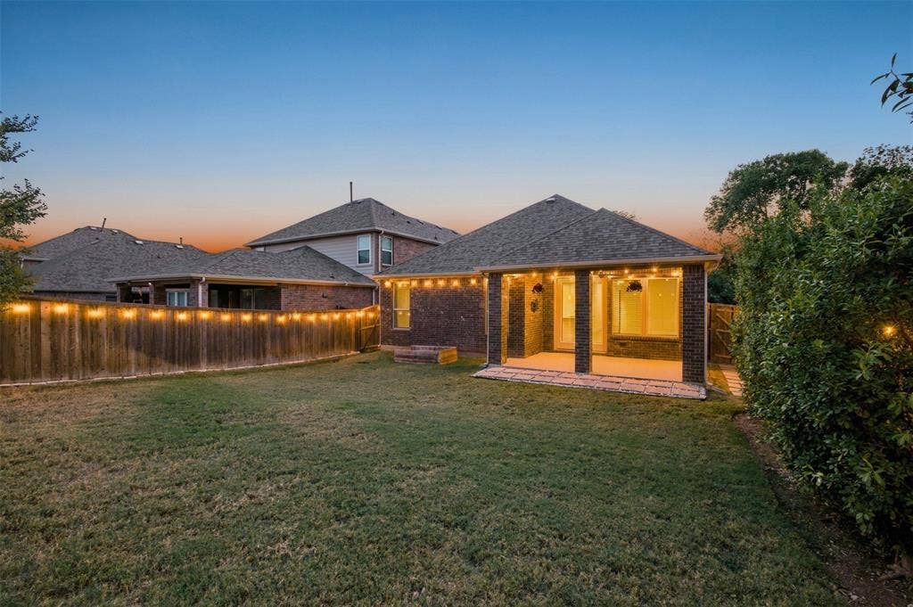 8028 Hickory Branch Drive, Frisco, TX 75034 Expansive backyard featuring a covered patio with brick columns, string lighting, and a wood privacy fence