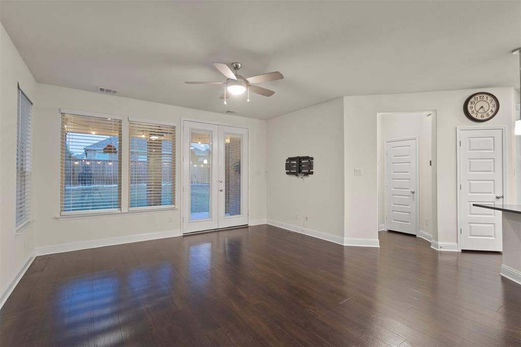 8028 Hickory Branch Drive, Frisco, TX 75034 Dark wood-finish flooring, white walls, ceiling fan with integrated lighting, glass-paned double doors, and multiple windows