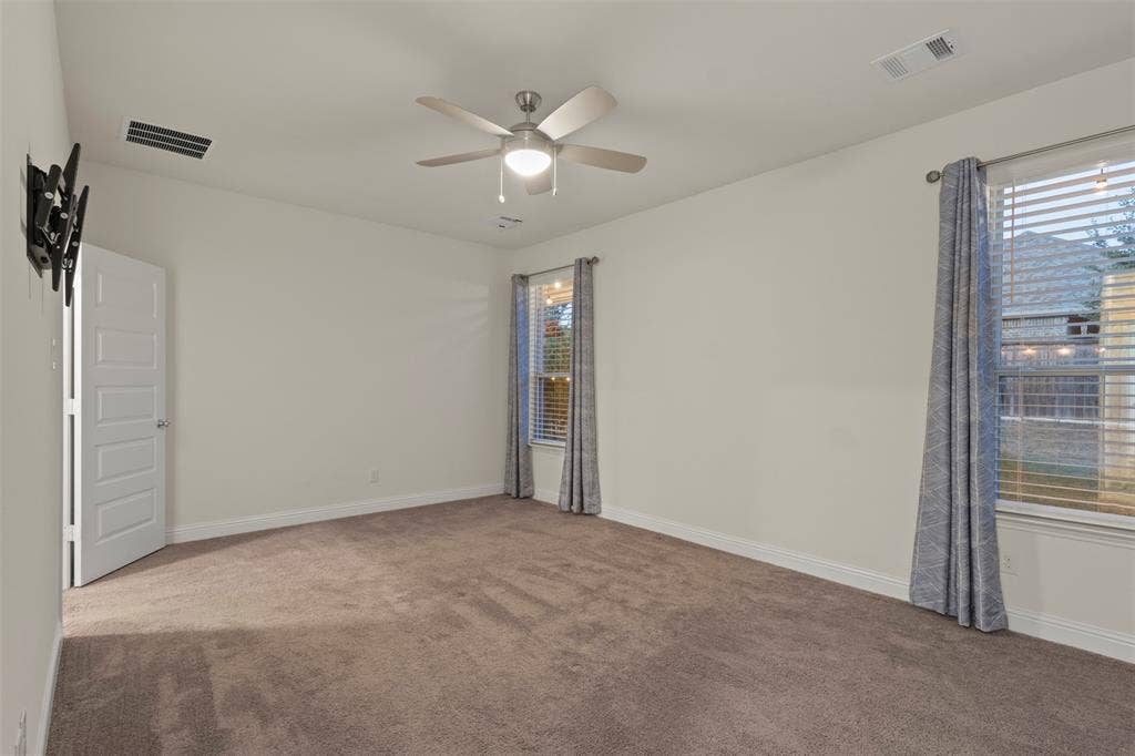 8028 Hickory Branch Drive, Frisco, TX 75034 Neutral tone walls, plush carpet flooring, two windows with blinds, ceiling fan with integrated lighting, and a white paneled door